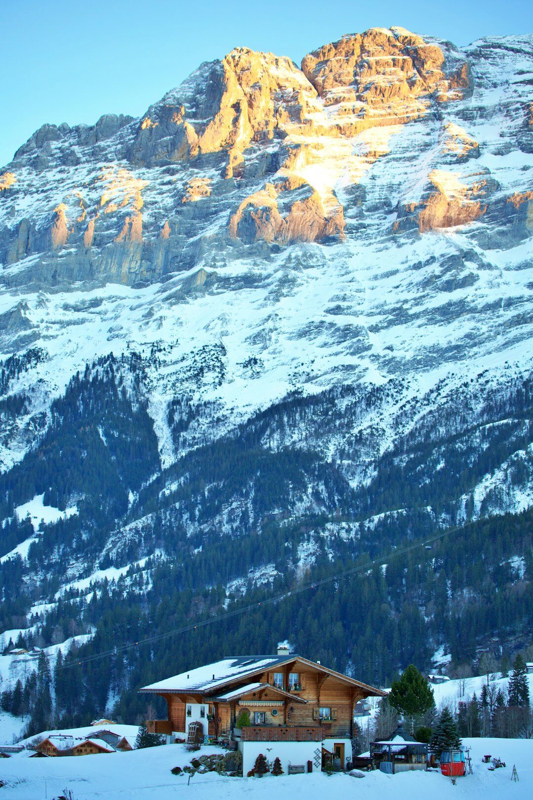 Luxuriöses Schweizer Chalet bei Dämmerung mit warmem Licht